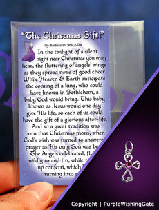 A poem titled 'The Christmas Gift' shown on a wallet-size card, and a tiny angel-like cross charm with a fuchsia crystal against a purple background.