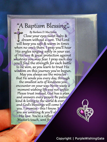 A wallet-size laminated card titled 'A Baptism Blessing,' and a crescent-shaped heart charm with a fuchsia crystal against a purple background.